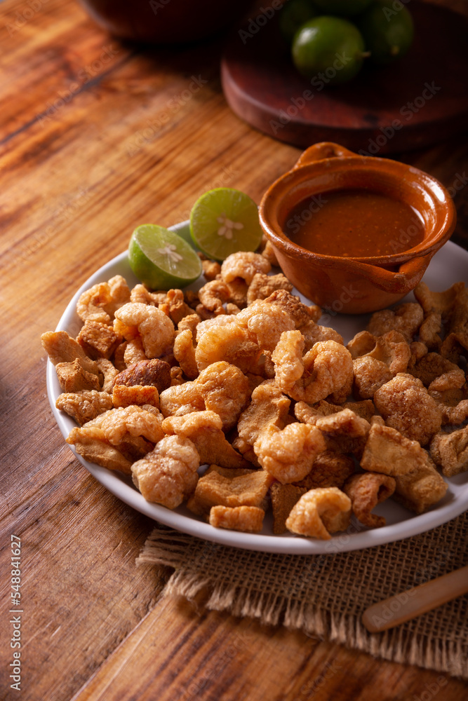 Chicharrones. Deep fried pork rinds, crispy pork skin pieces, traditional mexican ingredient or snack served with lemon juice and red hot chili sauce. Chicharrones. Deep fried pork rinds, crispy pork skin pieces, traditional mexican ingredient or snack served with lemon juice and red hot chili sauce.