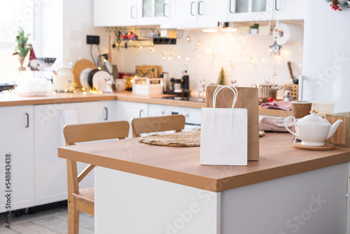 Food delivery service containers on table white scandi festive kitchen in christmas decor. Eve New year  saving time  too lazy to cook  hot order  disposable plastic box in fairy light. mock up