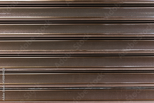 Detail shutter roller of a garage door made of metallic material or steel in dark cognac color. Modern security access business backdrop