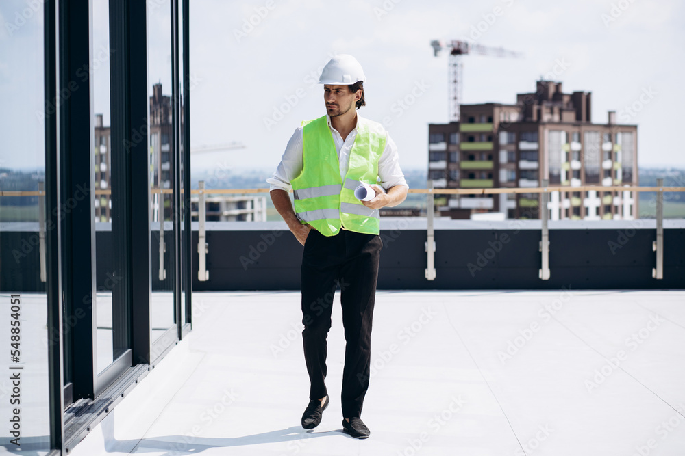 Business man in helmet standing on the roof of the building Business man in helmet standing on the roof of the building