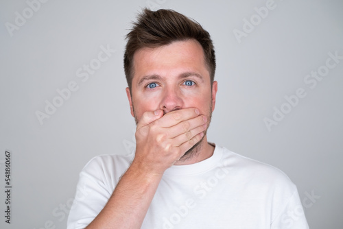 Keeping your secret. man covering mouth with hand and looking at camera.