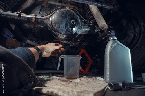 Changing the oil in the front differential of an off-road vehicle, truck with four-wheel drive. Car service. Tools and spare parts. Male hands, mechanic. View from the first person