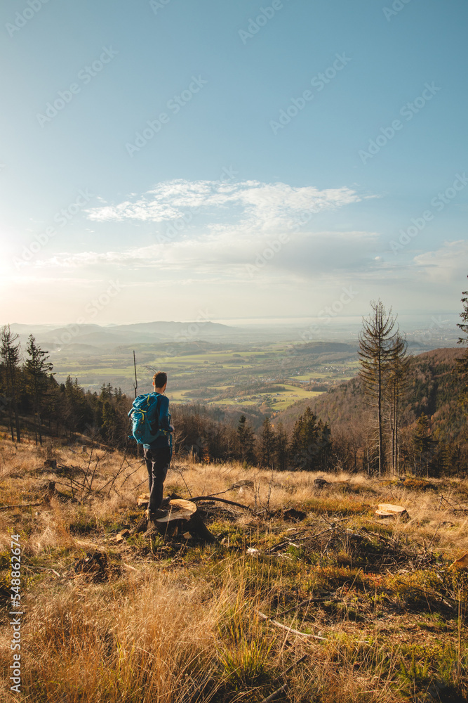 Enthusiastic traveller stands on a stump in a clear-cut forest, looking down into the valley, happy to have made it up another mountain. Reaching the goal. Beskydy mountains, Czech republic Enthusiastic traveller stands on a stump in a clear-cut forest, looking down into the valley, happy to have made it up another mountain. Reaching the goal. Beskydy mountains, Czech republic