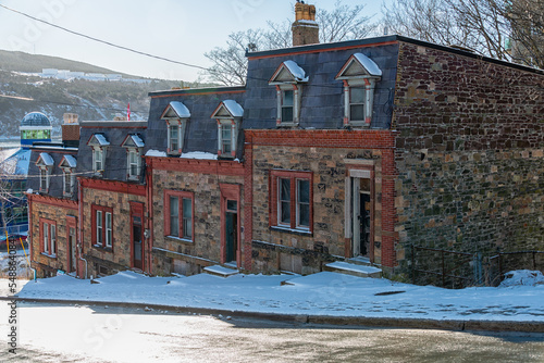 St. John's, Newfoundland, Canada-November 2022. The exterior of four rock structures adjoined. The houses are on a hill with snow covering the sidewalk. The brownstones are historic buildings. photo