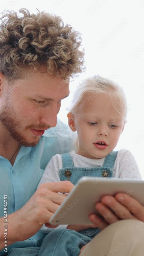 Handsome father and daughter looking at tablet and talking at home Handsome father and daughter looking at tablet and talking at home