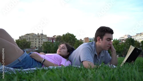 young caucasian woman and man student friends relaxing, having fun, reading and studying in the park
