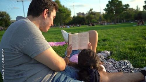 young caucasian woman and man student friends relaxing, having fun, reading and studying in the park