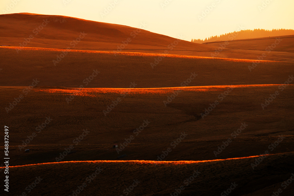 Sunset scenery in the Carpathian Bucegi mountains, Romania, Europe. Grassy hill in evening light.
