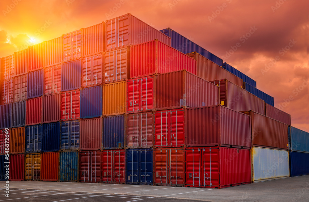Fototapeta premium Shipping containers being unloaded at port facilities at sunset - sunrise