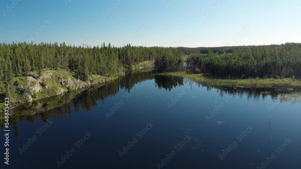 Drone aerial moving forward over a calm lake surrounded by boreal forest. The clear blue sky is perfectly reflected in the calm water.
Drone aerial moving forward over a calm lake surrounded by boreal forest. The clear blue sky is perfectly reflected in the calm water.