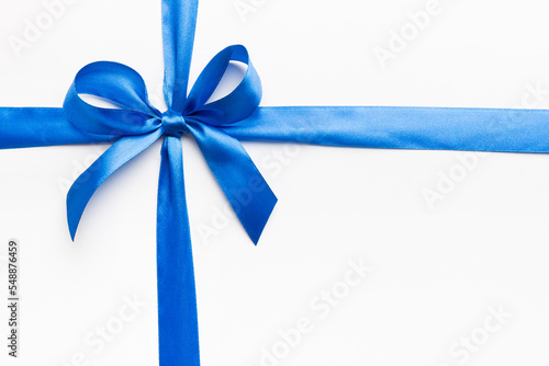 Top view of blue ribbon rolled and blue bow isolated on colored background. Flat lay with copy space