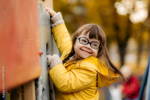 Fotografija Happy child with down syndrome enjoying swing on playground