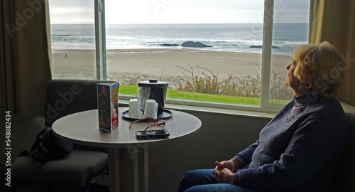 Reflection at the Beach - a woman in motel room enjoying the surf and ocean