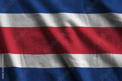 Costa Rica flag with big folds waving close up under the studio light indoors. The official symbols and colors in banner photo