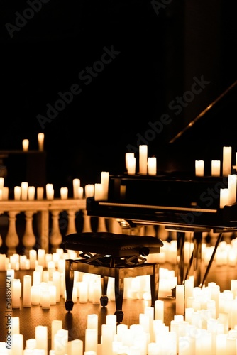 Chair and piano in a dark room surrounded by candles