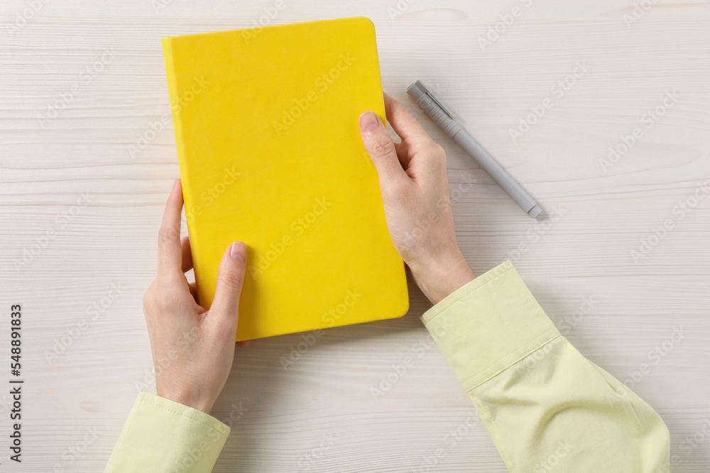 Woman with stylish notebook and pen at white wooden table, top view Woman with stylish notebook and pen at white wooden table, top view