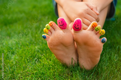 Teenage girl with smiling faces drawn on toes outdoors, closeup © New Africa