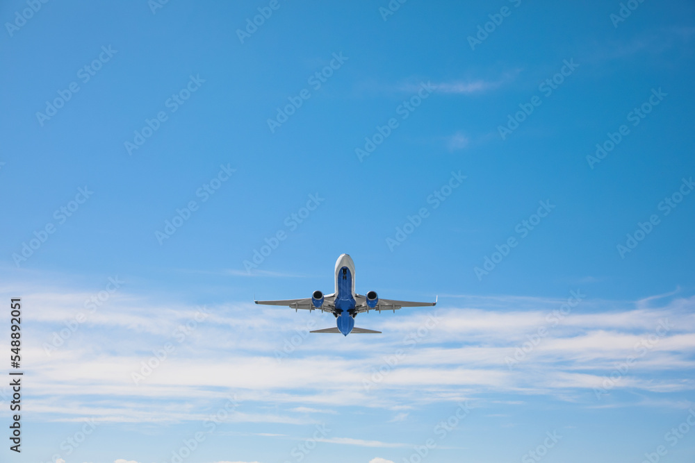 Fototapeta premium Modern white airplane flying in sky, low angle view