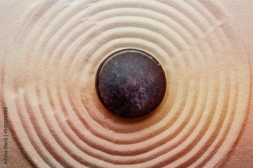 Naklejka premium Black stone on sand with pattern, top view. Zen, meditation, harmony