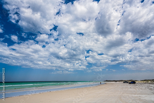 Lone woman walking on beach in Australia.  Long flat beach allows car access. Crystal clear water. Peaceful  solitude on Australian beach.