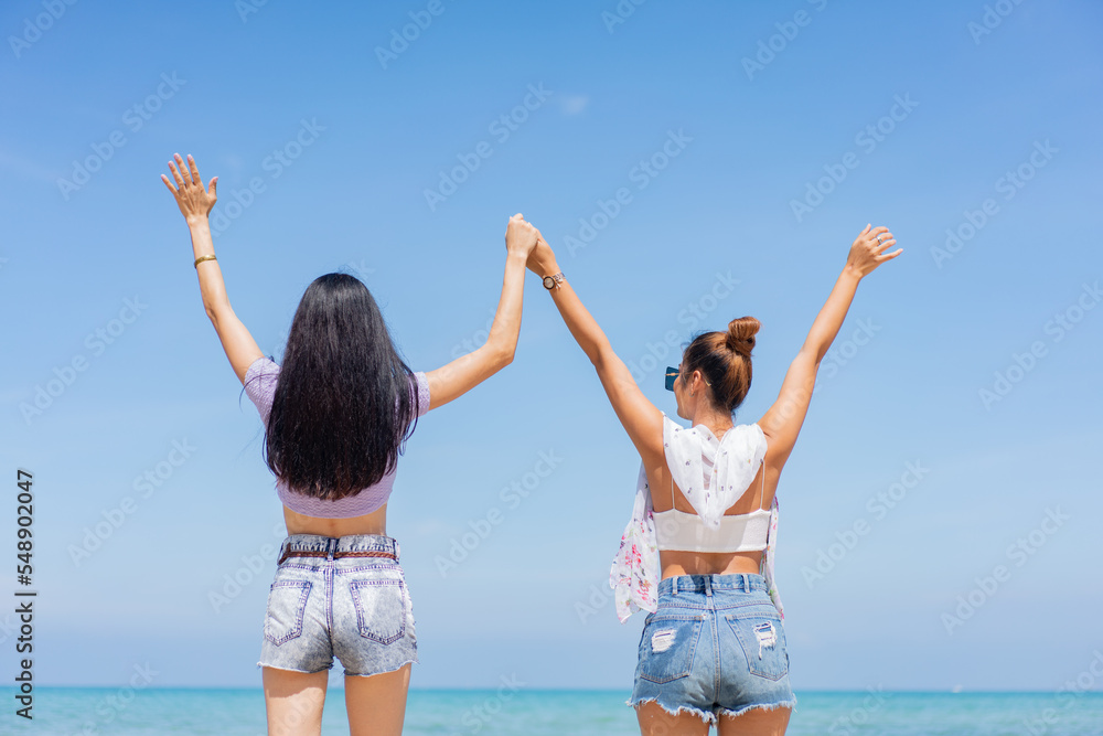 Two girlfriends hugging up and enjoying on the sea beach. A pair of girls in love cuddling on a tropical beach. romantic young lesbian couples in love and walking together on the beach.Concept of LGBT Two girlfriends hugging up and enjoying on the sea beach. A pair of girls in love cuddling on a tropical beach. romantic young lesbian couples in love and walking together on the beach.Concept of LGBT