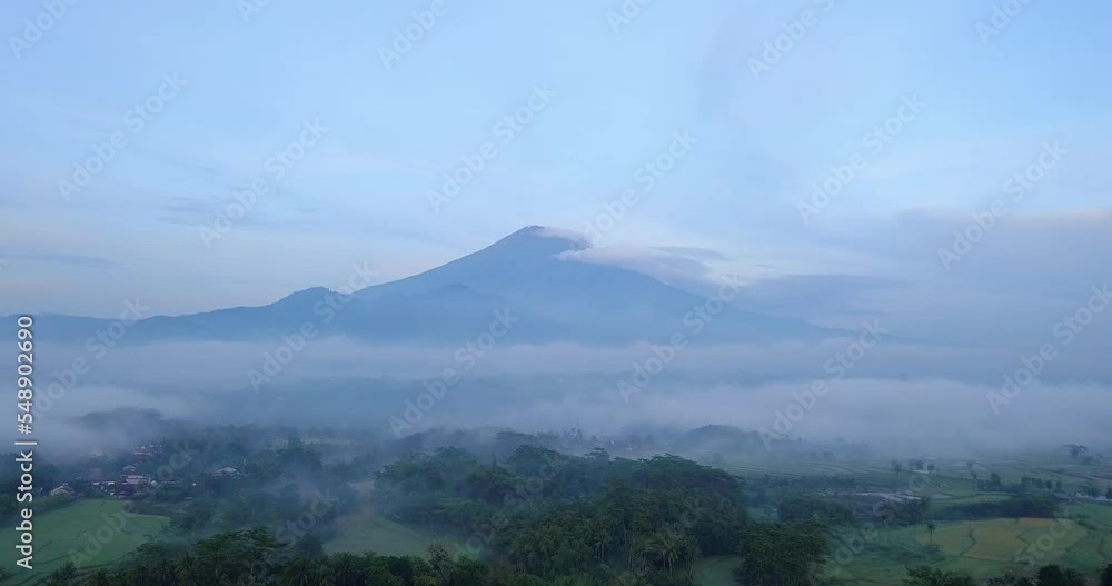 Aerial panorama view of foggy green landscape with Volcano in background in the morning - Mount Sumbing in Indonesia Aerial panorama view of foggy green landscape with Volcano in background in the morning - Mount Sumbing in Indonesia