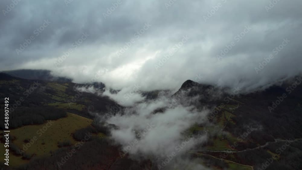 Clouds covering alpine valley in Autumn rainy day, dry grass meadows and leafless trees Clouds covering alpine valley in Autumn rainy day, dry grass meadows and leafless trees