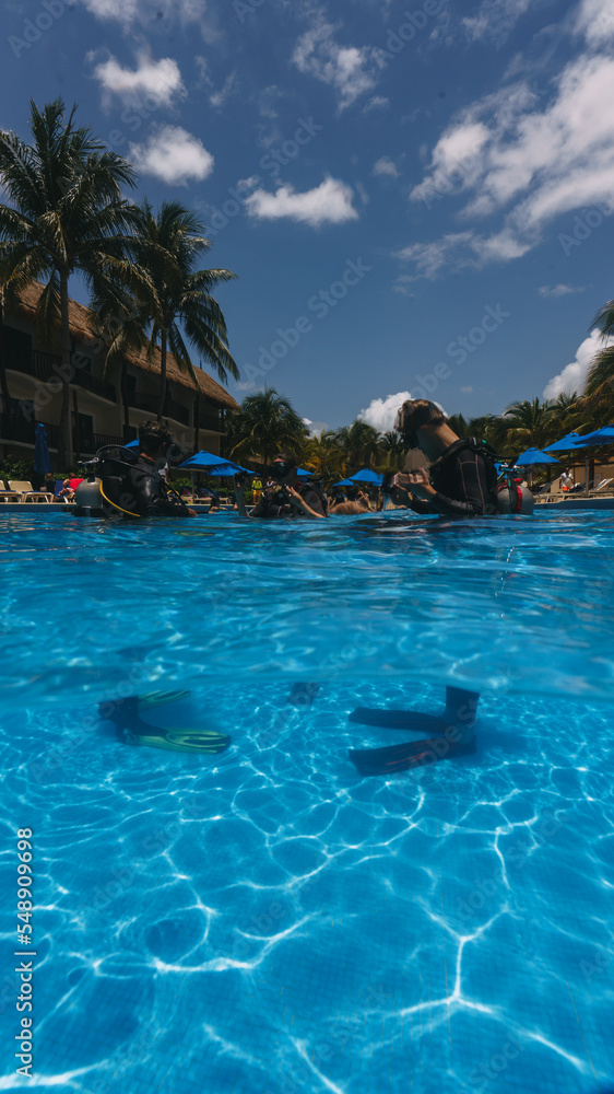 diving instructor teaches students to scuba dive in swimming pool. couple getting first experience with scuba diving under the guidance of experienced recreational diving instructor on vacation.