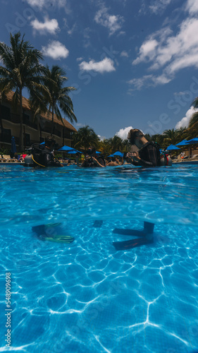 diving instructor teaches students to scuba dive in swimming pool. couple getting first experience with scuba diving under the guidance of experienced recreational diving instructor on vacation.