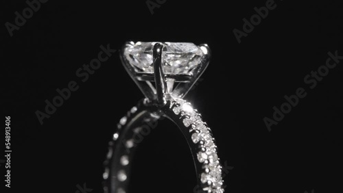 Close up, diamond engagement ring rotating against black studio background photo
