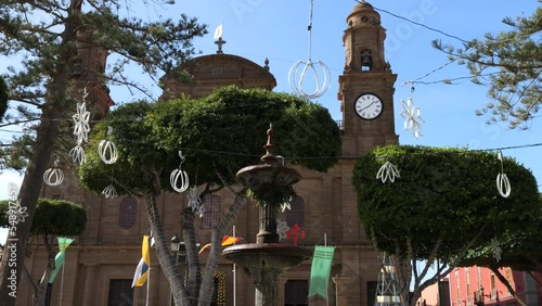 Cinematic shot of the fountain located in the Plaza de los Faycanes and at the bottom of the Galdar church and where flags can be seen waving on the masts. On the island of Gran Canaria. photo
