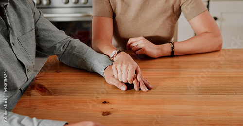 Support, holding hands and couple with marriage, home and mental health problem zoom on table for help, trust and love. Sad people hand holding for depression, death or bad news with care and empathy