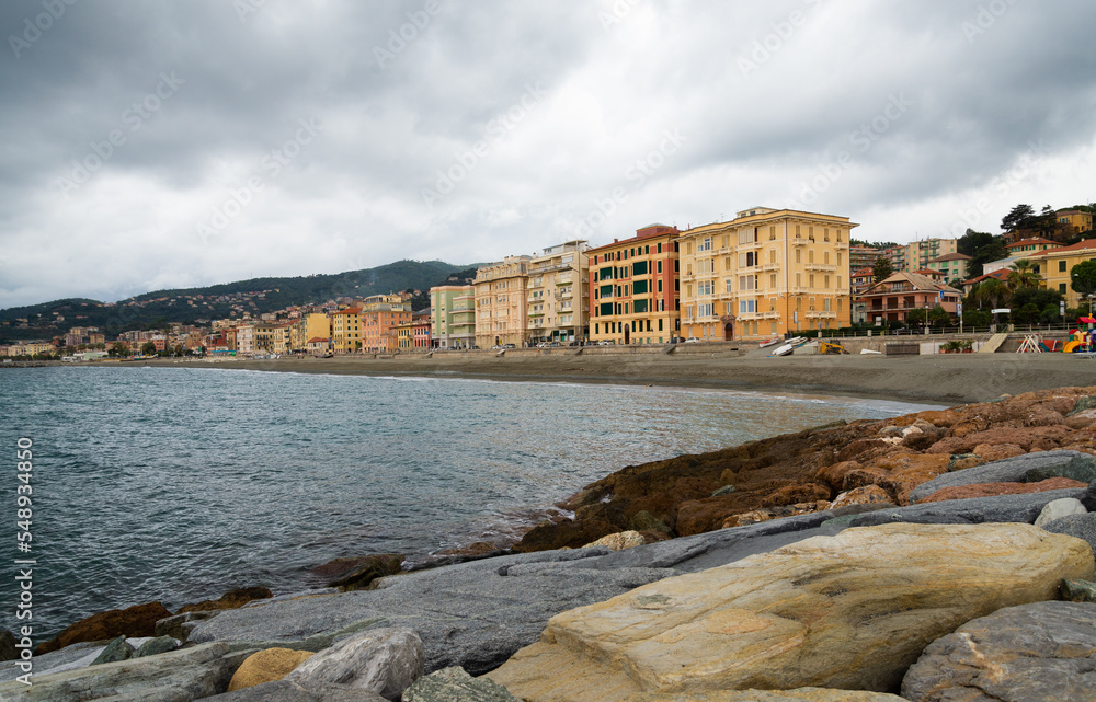 The coastline of Varazze, a vacation village on the mediterranean sea, in Liguria, Italy. Rocks and stones in the foreground. Dramatic sky in the background.