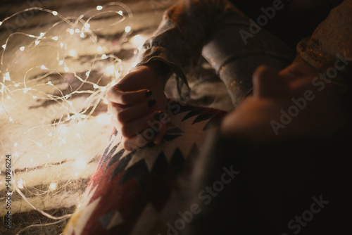Close up dreaming woman lying near light bulb garland concept photo. Cozy mood. Top view photography with blurred background. High quality picture for wallpaper, travel blog, magazine, article © Gypsy On The Road