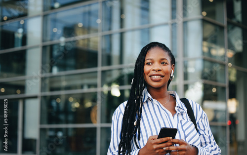 Obraz na plátně Pensive business woman holding a smartphone and wearing earphones during her mor