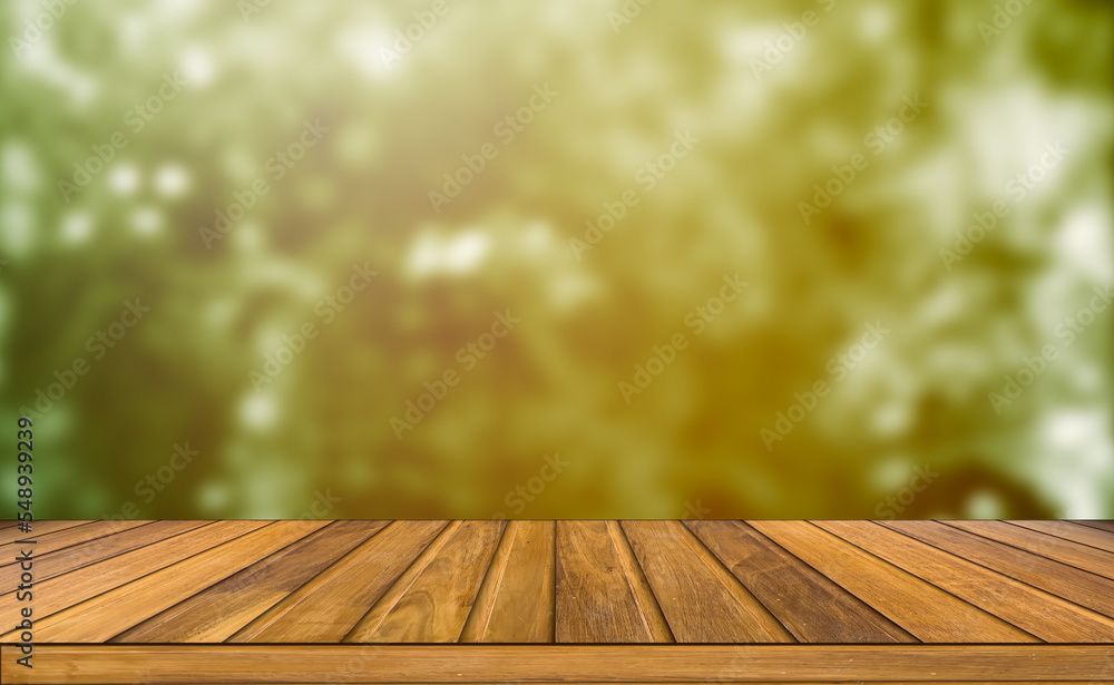 A modern wooden table top outdoor setting contrasts with garden orange sunset blurred background. A modern wooden table top outdoor setting contrasts with garden orange sunset blurred background.