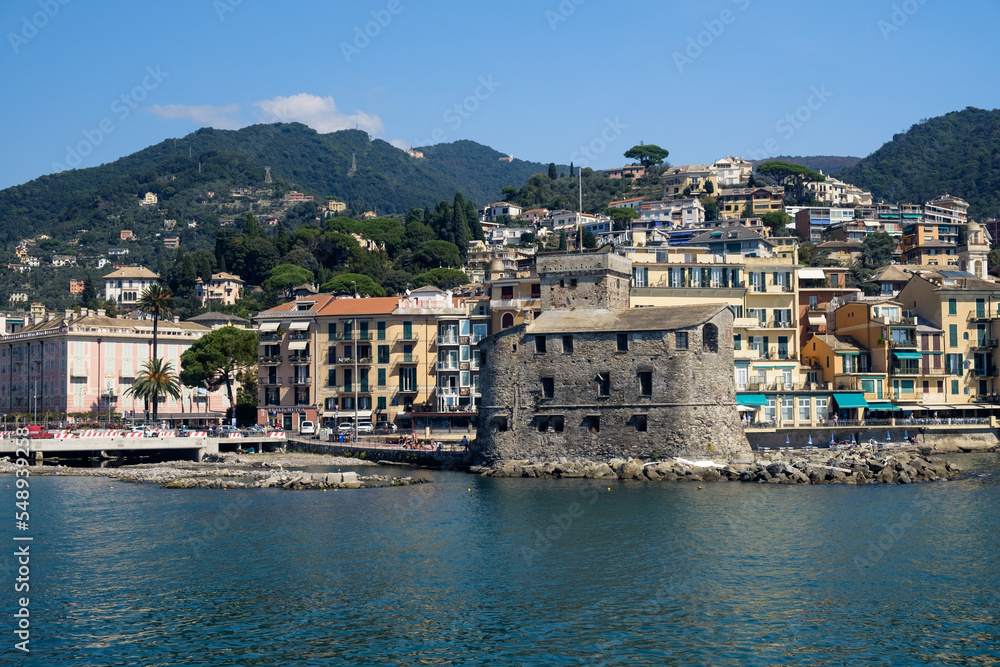 The castle and the hilly coastline with buildings in Rapallo, Liguria, Italy.