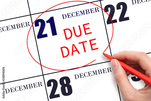Hand writing text DUE DATE on calendar date December 21 and circling it. Payment due date