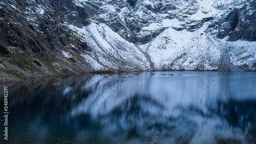Czarny Staw pod Rysamy or Black Pond lake near the Morskie Oko Snowy Mountain Hut in Polish Tatry mountains, drone view, Zakopane, Poland. Aerial view shot of beautiful green hills and mountains in