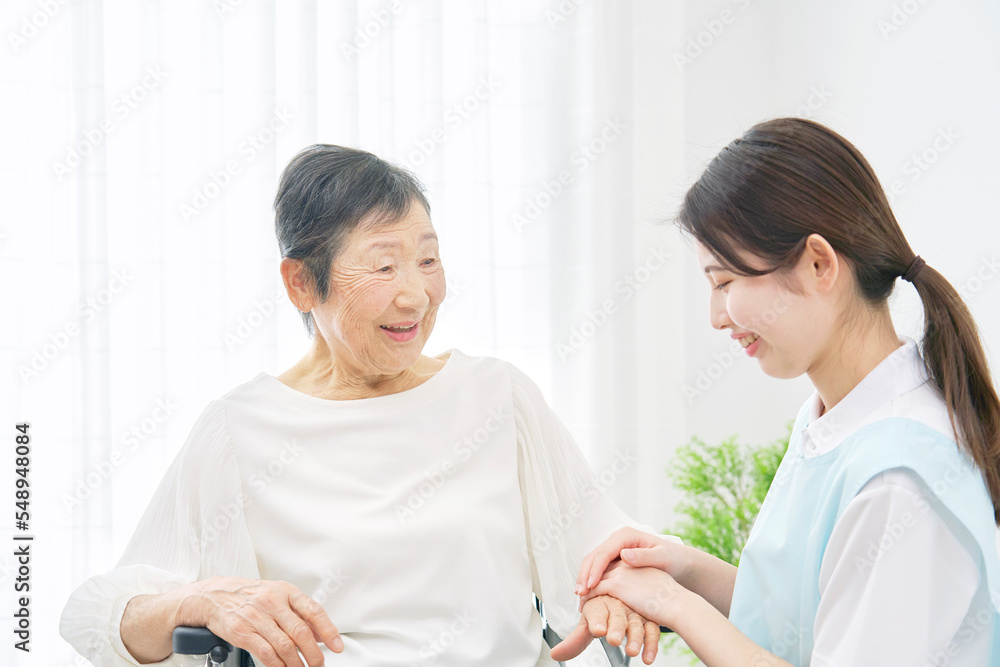 Fototapeta premium 車椅子に乗る高齢者女性と会話する介護士