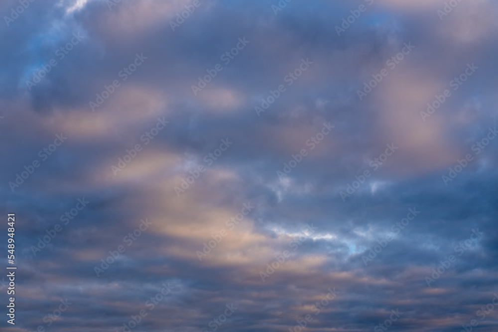 Beautiful sunset or sunrise sky, illuminating dark blue and pale pink clouds. Cloudy sky to overlay on your photos.