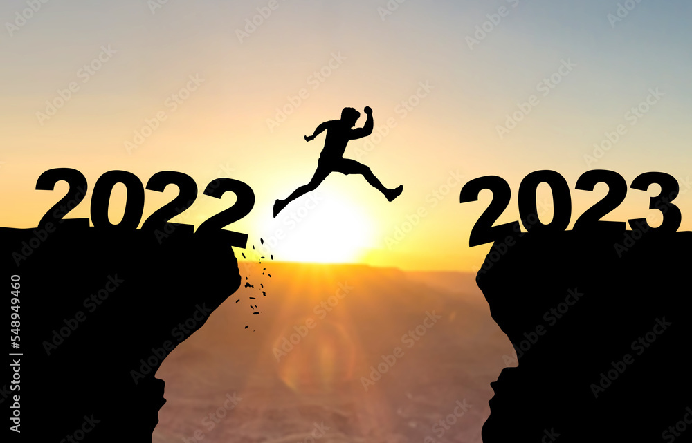 Man jumps over abyss with sunset in background and inscription 2022 and 2023 Man jumps over abyss with sunset in background and inscription 2022 and 2023