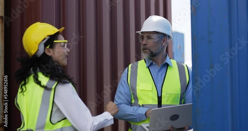 Handheld panning shot, middle-aged Caucasian business manager man and pretty engineer female are checking transport container and use laptop computer at storage port terminal