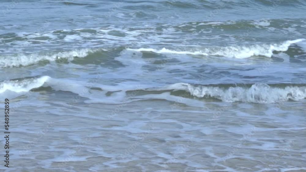 slow motion of foamy waves rolling towards the sand beach, golden beach meeting deep blue ocean water and foamy waves. turquoise sea waves breaking on the sandy coastline. slow motion of foamy waves rolling towards the sand beach, golden beach meeting deep blue ocean water and foamy waves. turquoise sea waves breaking on the sandy coastline.