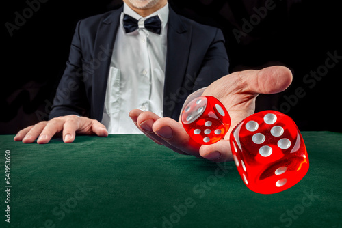 Gambling concept. Close up of male hand throwing dice at casino, gambling club. Сasino chips or Casino tokens, poker cards, gambling man spending time in games of chance photo