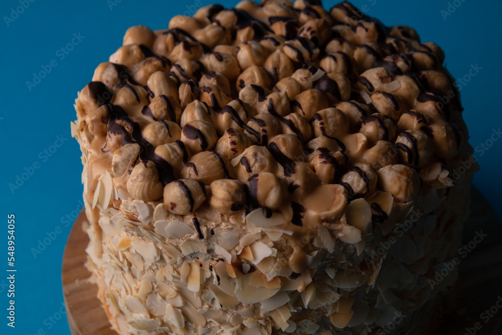 Photo of a whole walnut cake on a wooden board on a blue background Photo of a whole walnut cake on a wooden board on a blue background