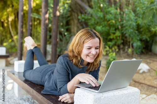 A beautiful freelancer woman works at the park using a computer.