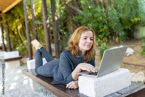 A beautiful freelancer woman works at the park using a computer.