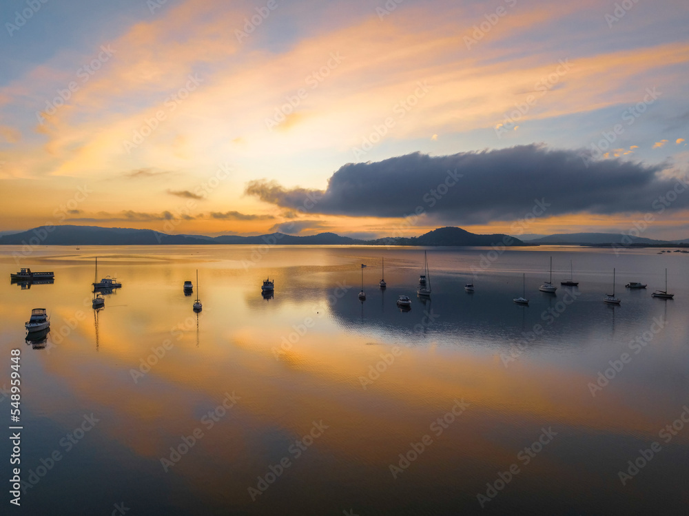 Sunrise over the water with fog, boats, clouds and reflections