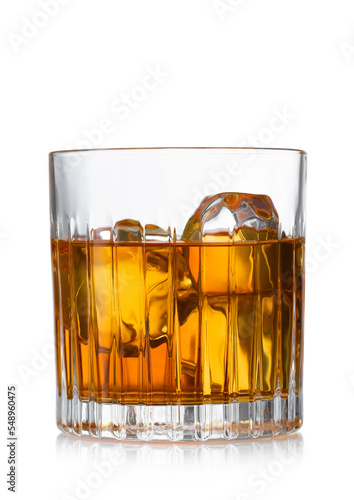 Crystal old fashioned glass with whiskey and ice cubes on white background.